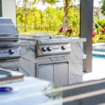 An outdoor Florida kitchen with outdoor kitchen appliances, a stainless steel bbq grill, and a pool