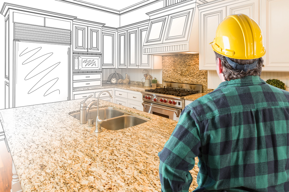 An outdoor kitchen contractor in a yellow helmet thinking about the outdoor kitchen design.