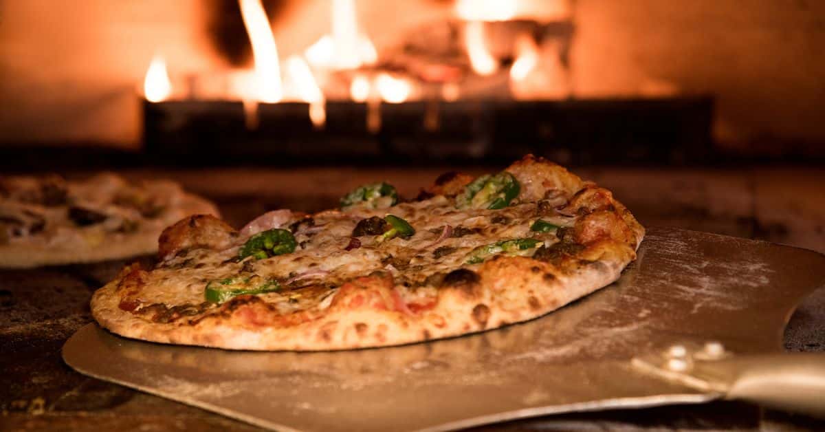 Wood-fired pizza cooking inside an outdoor kitchen with pizza oven