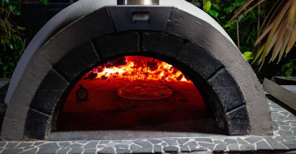 Outdoor Kitchen Pizza Oven with Glowing Fire - Paradise Outdoor Kitchens Outdoor kitchen pizza oven with fire and pizza baking inside