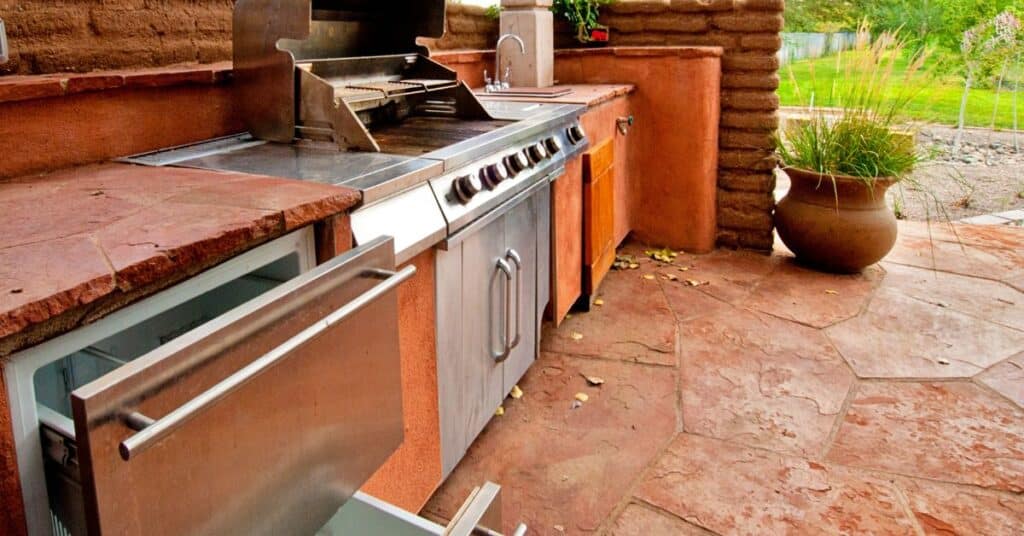 Built-in stainless steel gas grill with side burners installed in outdoor kitchen