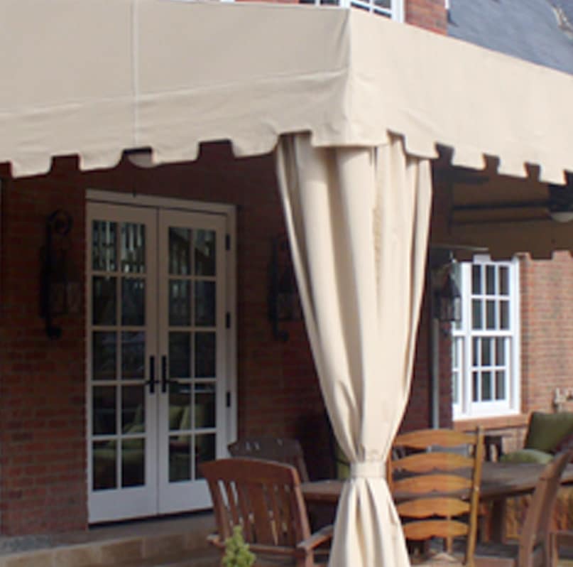 Fixed Outdoor Awning for Patio or Kitchen Area - Paradise Outdoor Kitchens Fixed outdoor awning with support posts and curtains providing shade over a patio seating area.